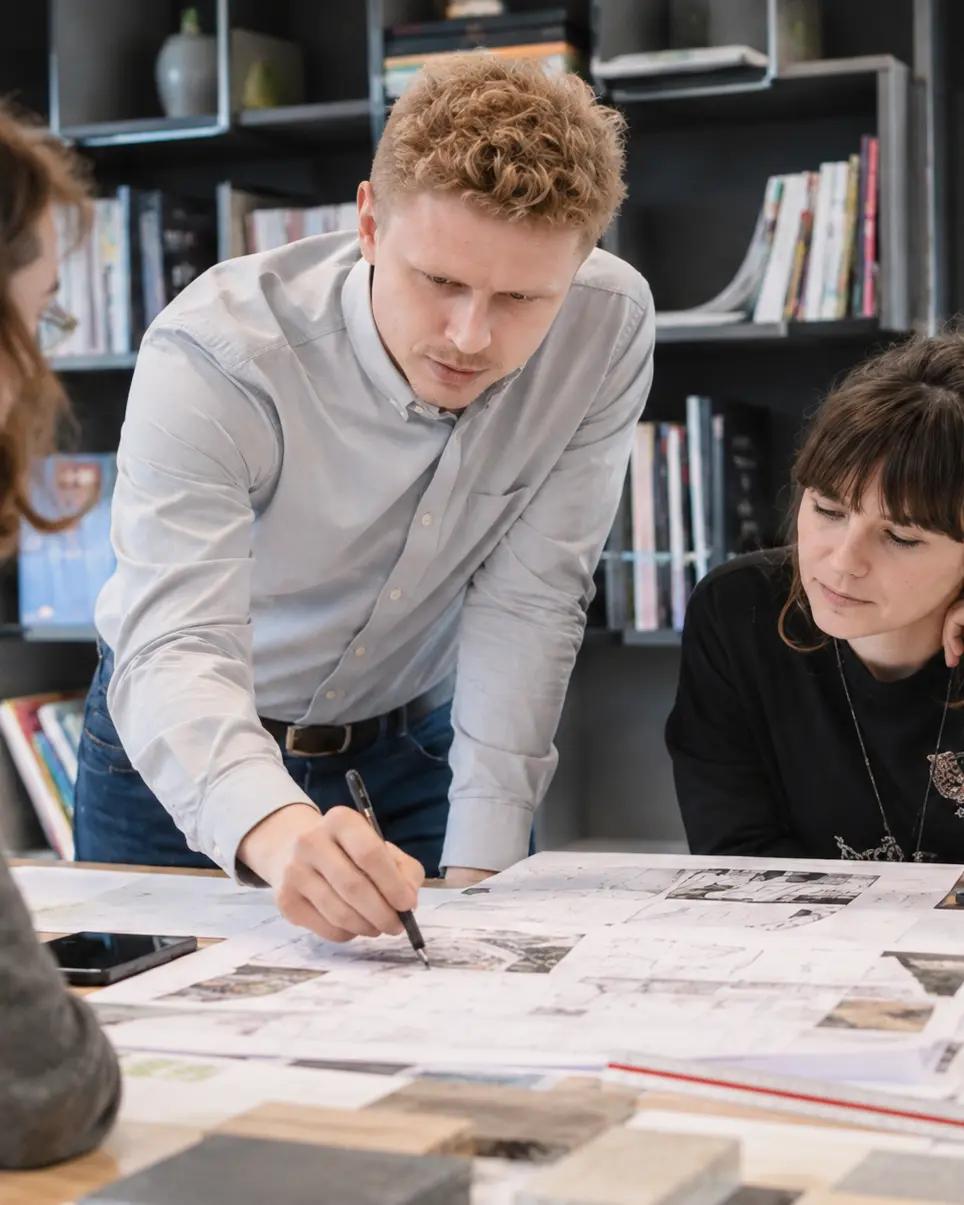 Michal Matlon reviewing architectural plans with two people at a table.