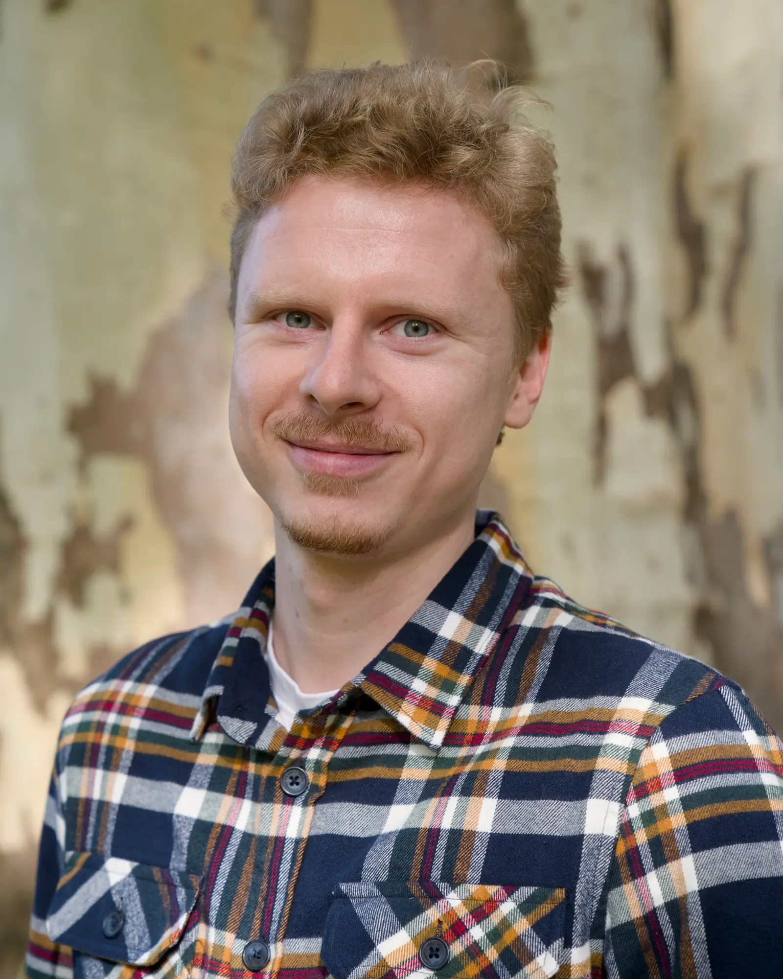 Portrait of Michal Matlon in a plaid shirt.