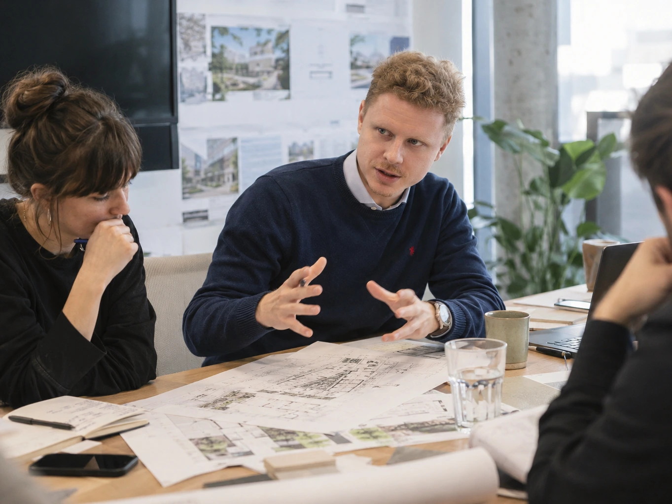 Michal Matlon discussing architectural plans with two people at a table.